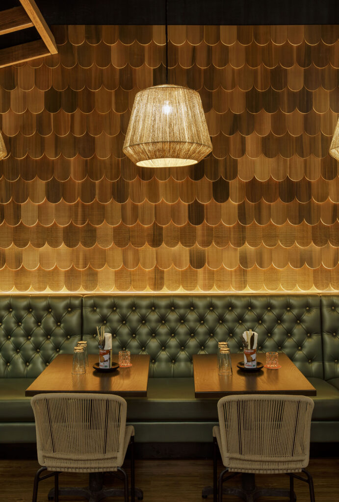 Shore Leave, a Boston hospitality project designed by Matthew Arnold, featuring tropical-inspired interiors. Cozy alcove booth seating with ambient lighting at Shore Leave, designed to enhance guest experience.